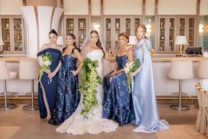 Bride with bridesmaids in blue floral and dusty blue gowns holding bouquets at Wave Resort in Long Branch, NJ.