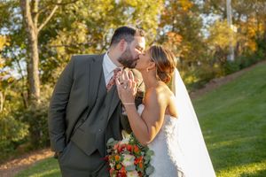 Bride and groom sharing a romantic kiss outdoors with colorful autumn foliage in the background at Mountain Creek in Vernon, NJ.