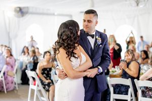 Couple sharing romantic first dance at elegant white tent wedding reception with guests watching at The Estate at Eagle Lake.