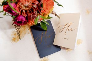 Elegant His and Her wedding vow books beside vibrant colorful bridal bouquet at Tourelay Farm in Colts Neck, NJ.