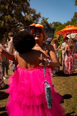 Two women in vibrant pink tulle skirts and festive hats celebrate at Azalea Festival garden party event in Airlie Gardens, Wilmington NC