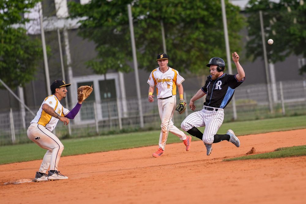 Baseball player sliding into base as infielder prepares to catch the ball during a competitive game.