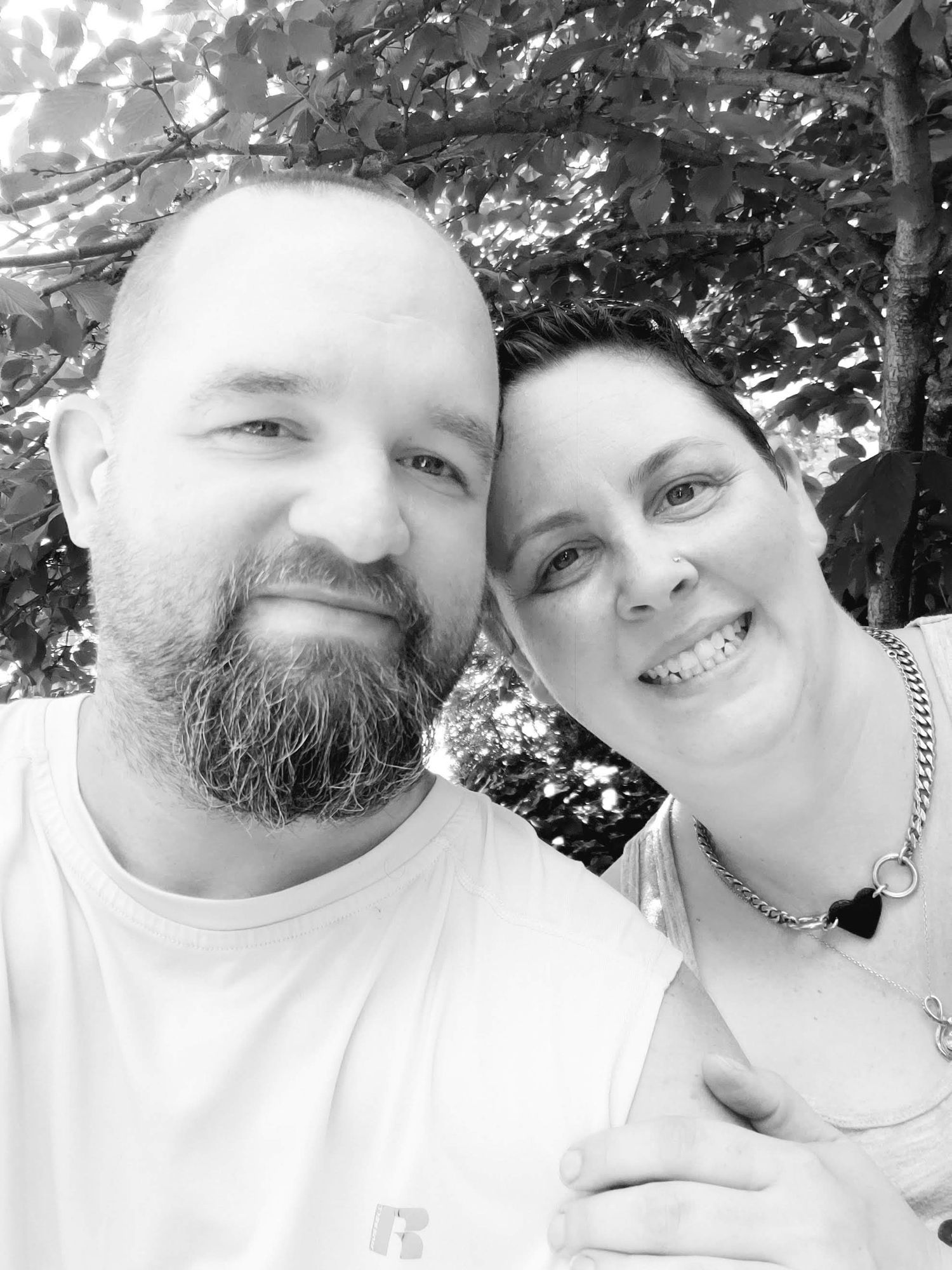 Black and white portrait of a smiling couple taking a close-up selfie outdoors
