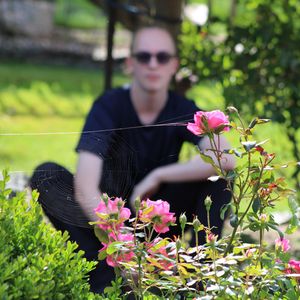 Person sitting outdoors surrounded by flowers during a soft and natural lifestyle portrait session