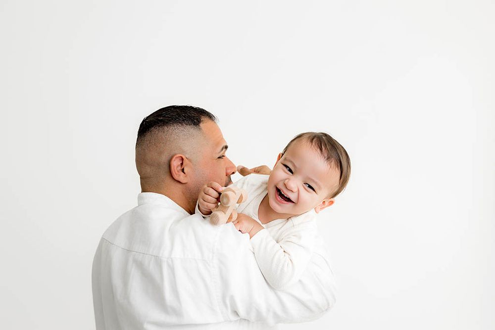 Dad holding up his 2 year old smiling little boy for 2nd birthday photoshoot.