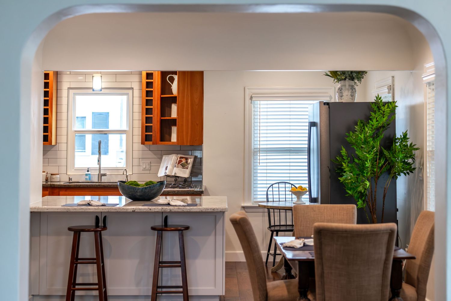Modern kitchen with bar seating, wine rack, granite countertops, and adjacent dining area with natural light.