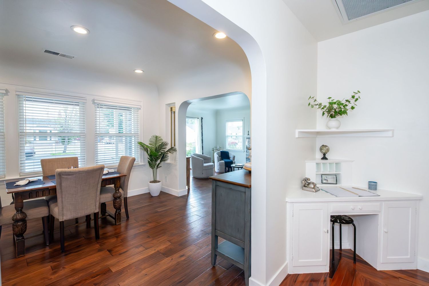 Bright open-concept home with hardwood floors, dining area, arched doorway, and built-in white desk nook.