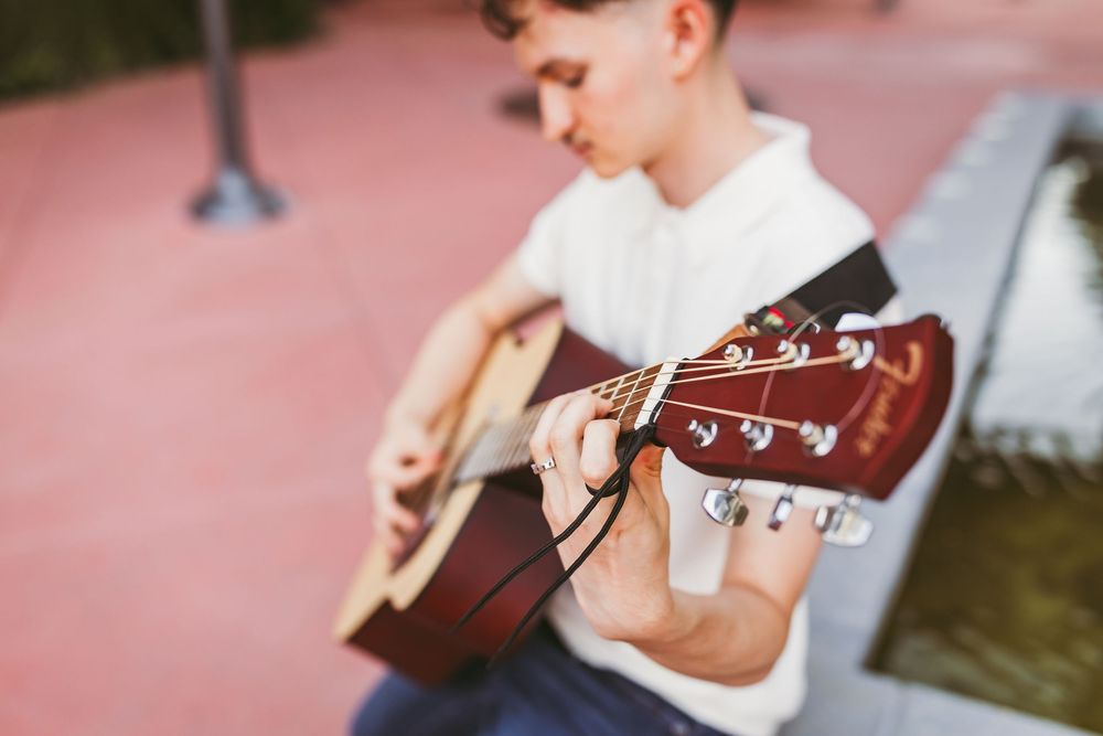 high school senior playing a guitar in downtown redlands for graduation photos
