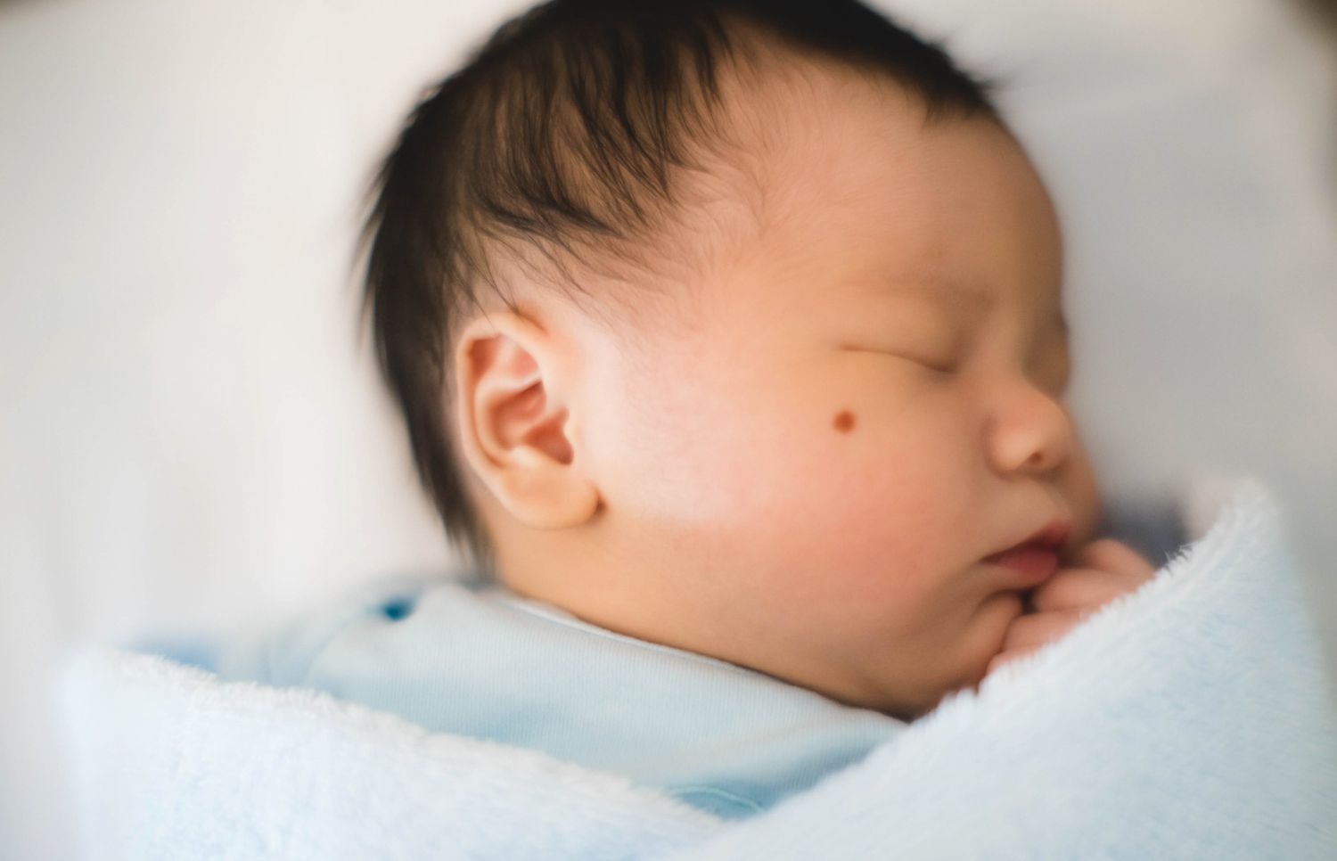 A sleeping baby lies peacefully against soft white bedding in a series of gentle poses熟睡的嬰兒以一系列柔和的姿勢，平靜地躺在柔軟的白色床單上。
