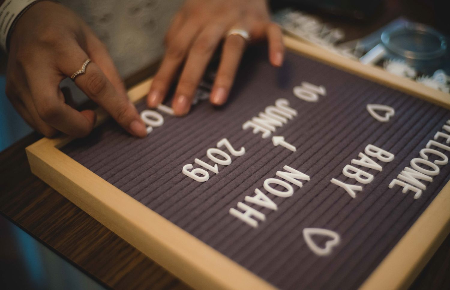 Close-up view of hands arranging letters and numbers on a black felt letter board.特寫鏡頭：雙手在黑色毛氈字母板上排列字母和數字。
