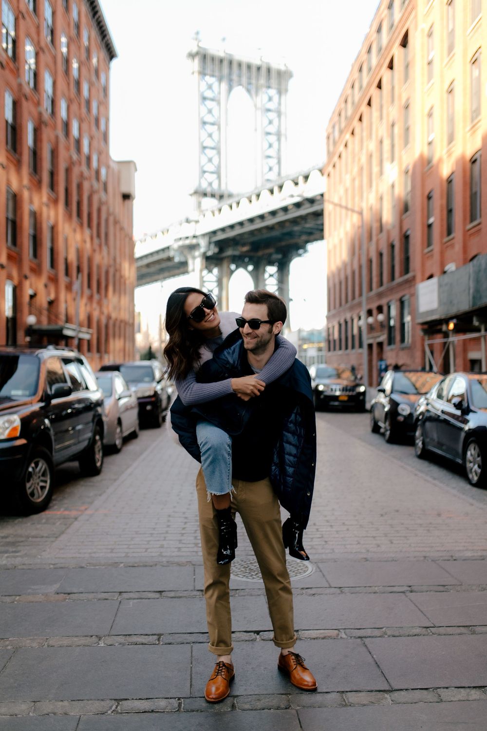 Couple posing on a Brooklyn street with the Manhattan Bridge in the background, DUMBO NYC.