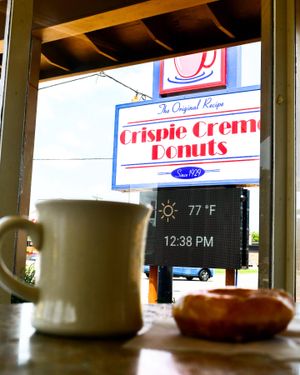 Coffee mug and donut at a Crispie Cream Donuts shop with temperature display showing 77°F.