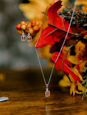 Delicate crystal necklace and earring set displayed with autumn leaves and berries.
