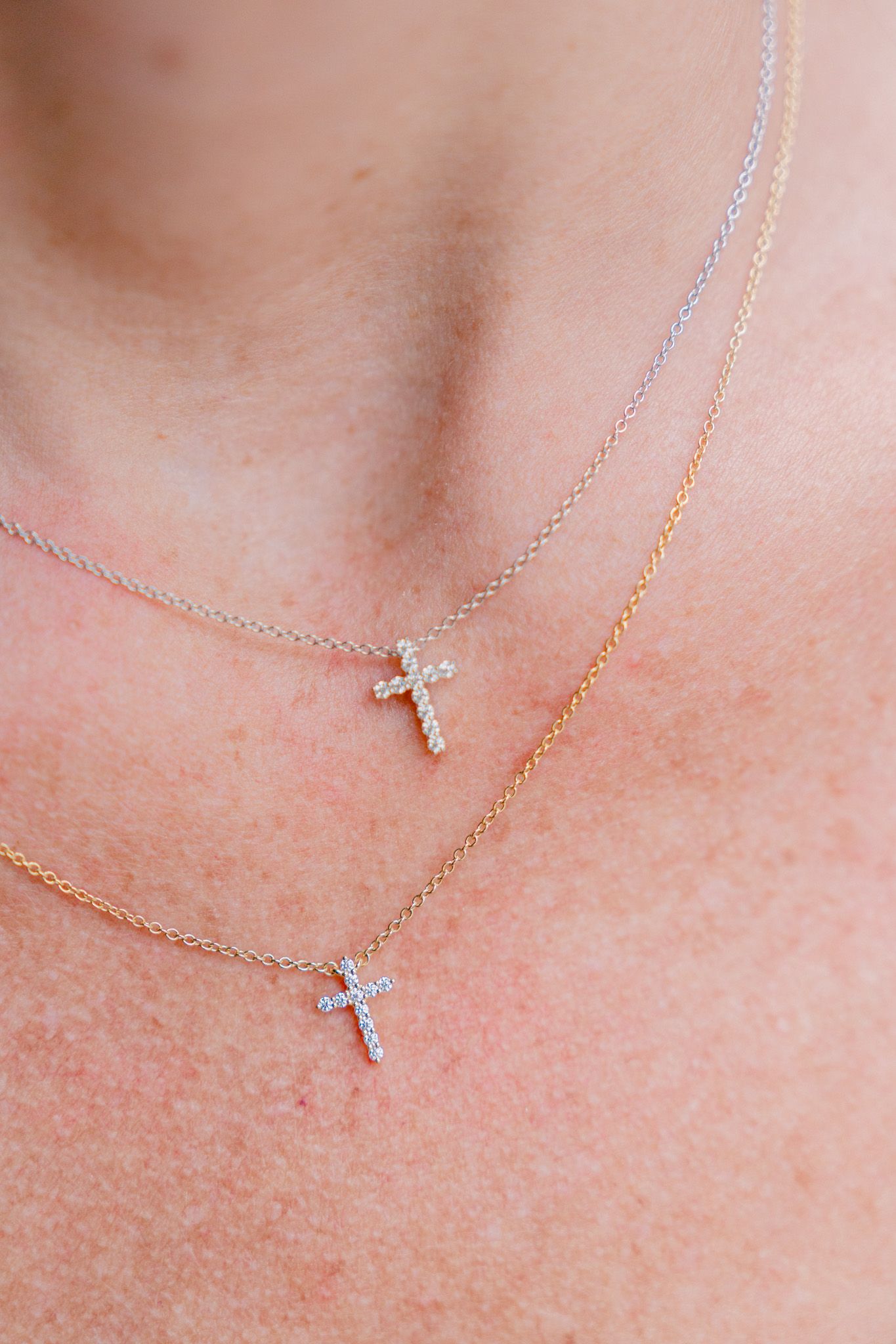Layered delicate cross necklaces in silver and gold with crystal accents.