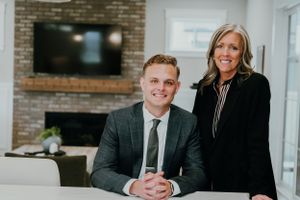 Professional team members pose in modern office with exposed brick and TV in background.