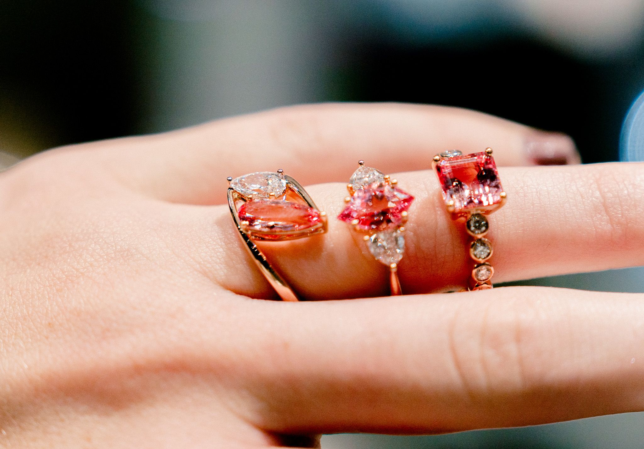 Three rose gold and crystal engagement rings displayed on a finger.