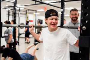 Person exercising with a barbell at a modern fitness facility.