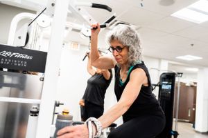 Active senior exercising on fitness equipment in modern gym facility.