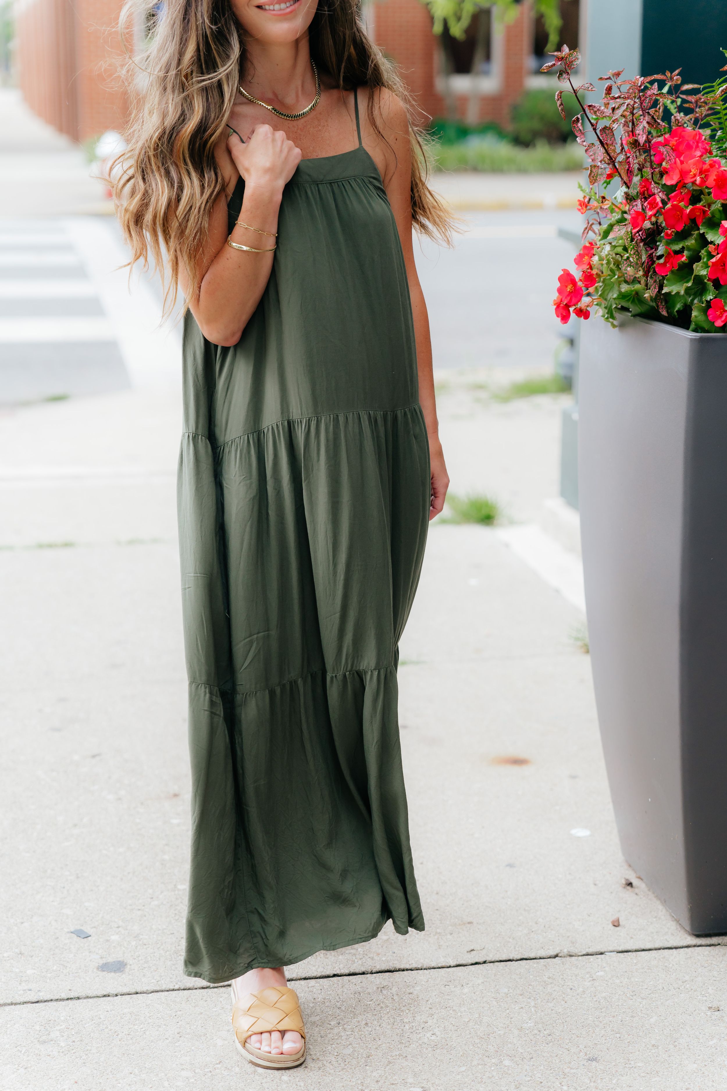 Flowing olive green tiered maxi dress styled with casual sandals and delicate jewelry.