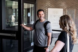 Person greeting someone at entrance of fitness facility.