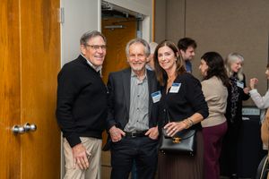 Three people pose together at a networking event in a casual indoor setting.