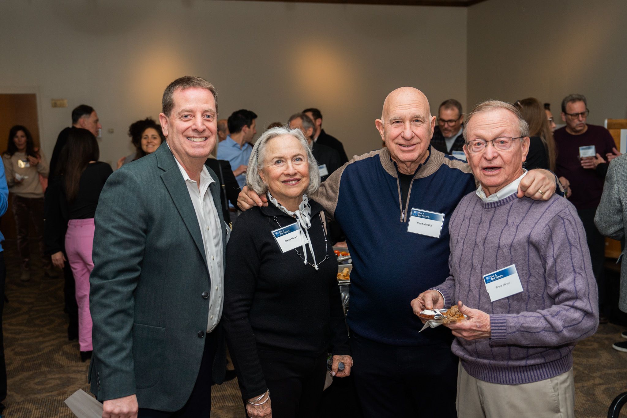Four people wearing name tags gather at an indoor networking event.