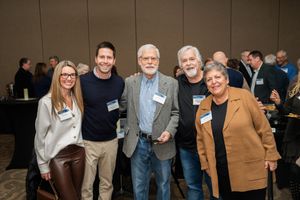 Group of people with name tags socializing at an indoor business gathering.