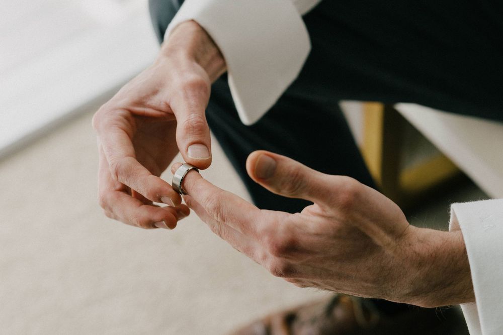 Close up of hands exchanging wedding rings during ceremony.