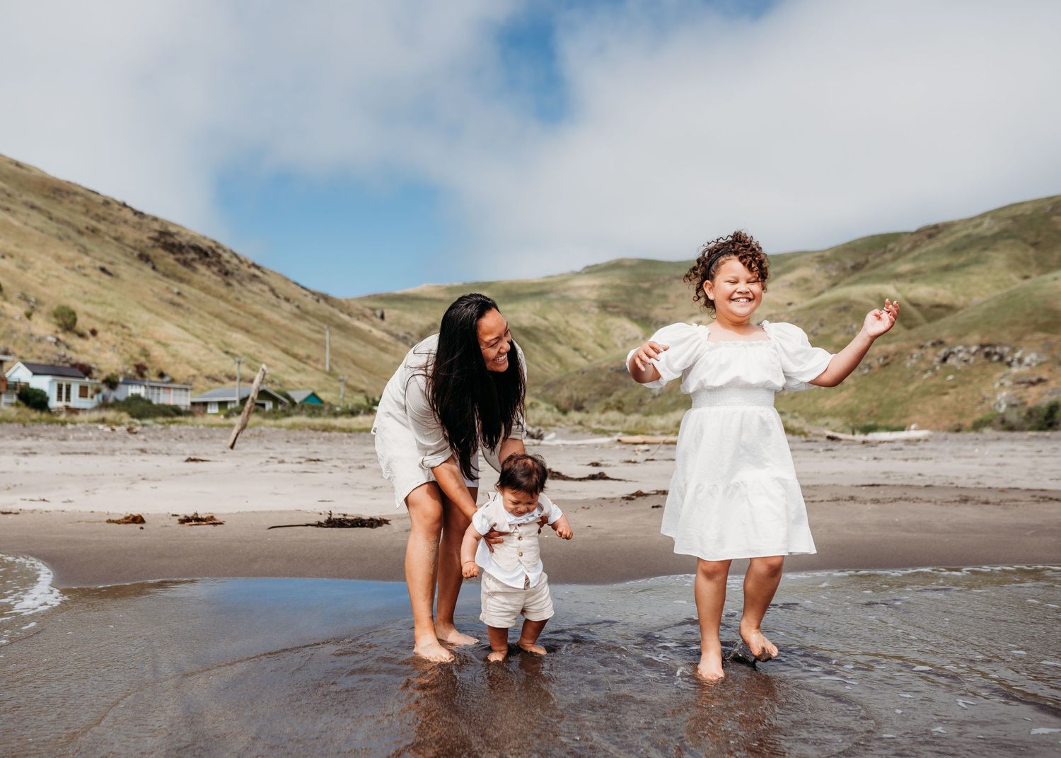 Family playing together at the beach with mountains visible in the background.