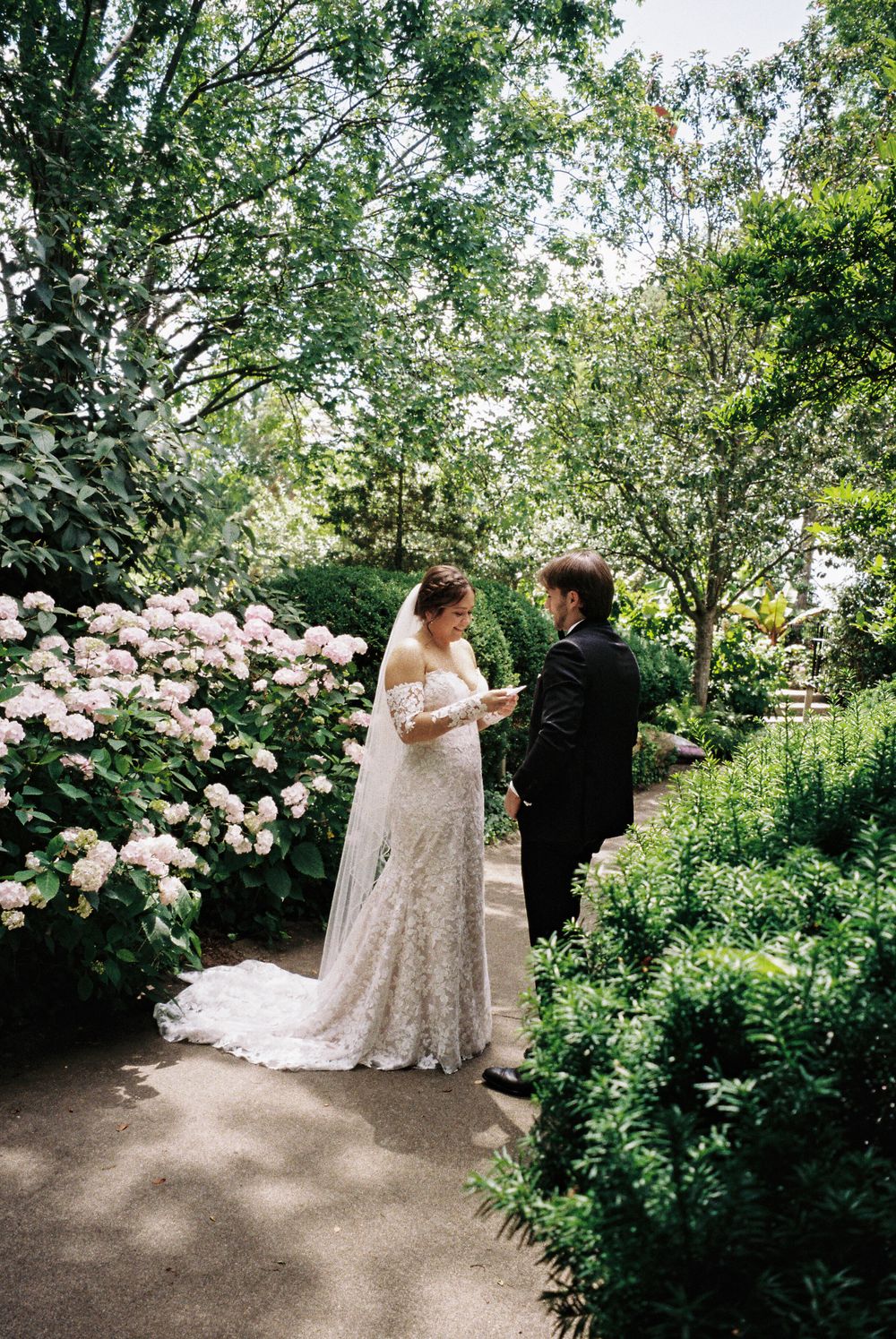 A tender moment between newlyweds on a garden path surrounded by blooming flowers.