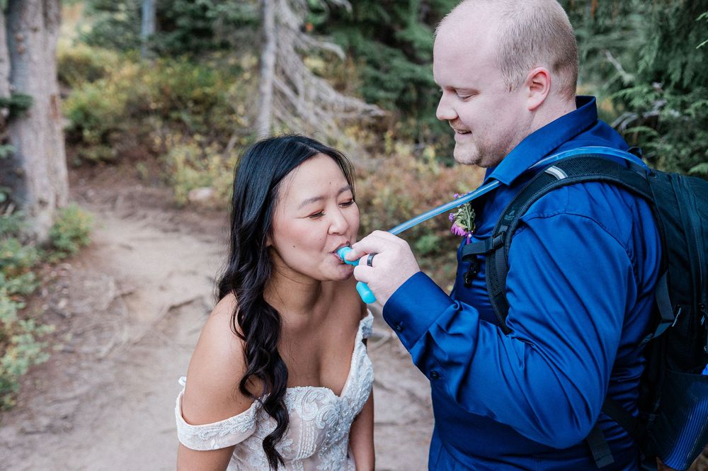 groom giving water to his bride during a hiking elopement