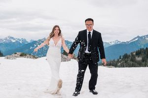 bride and groom holding hands while laughing and kicking up snow during elopement