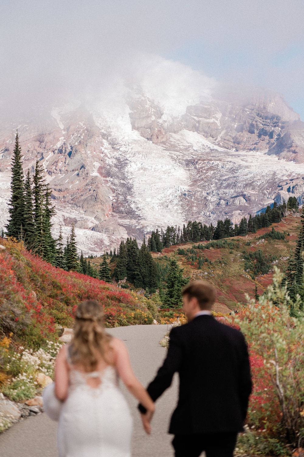 bride and groom holding hands with the focus on Mt. Rainier in the background during fall elopement.