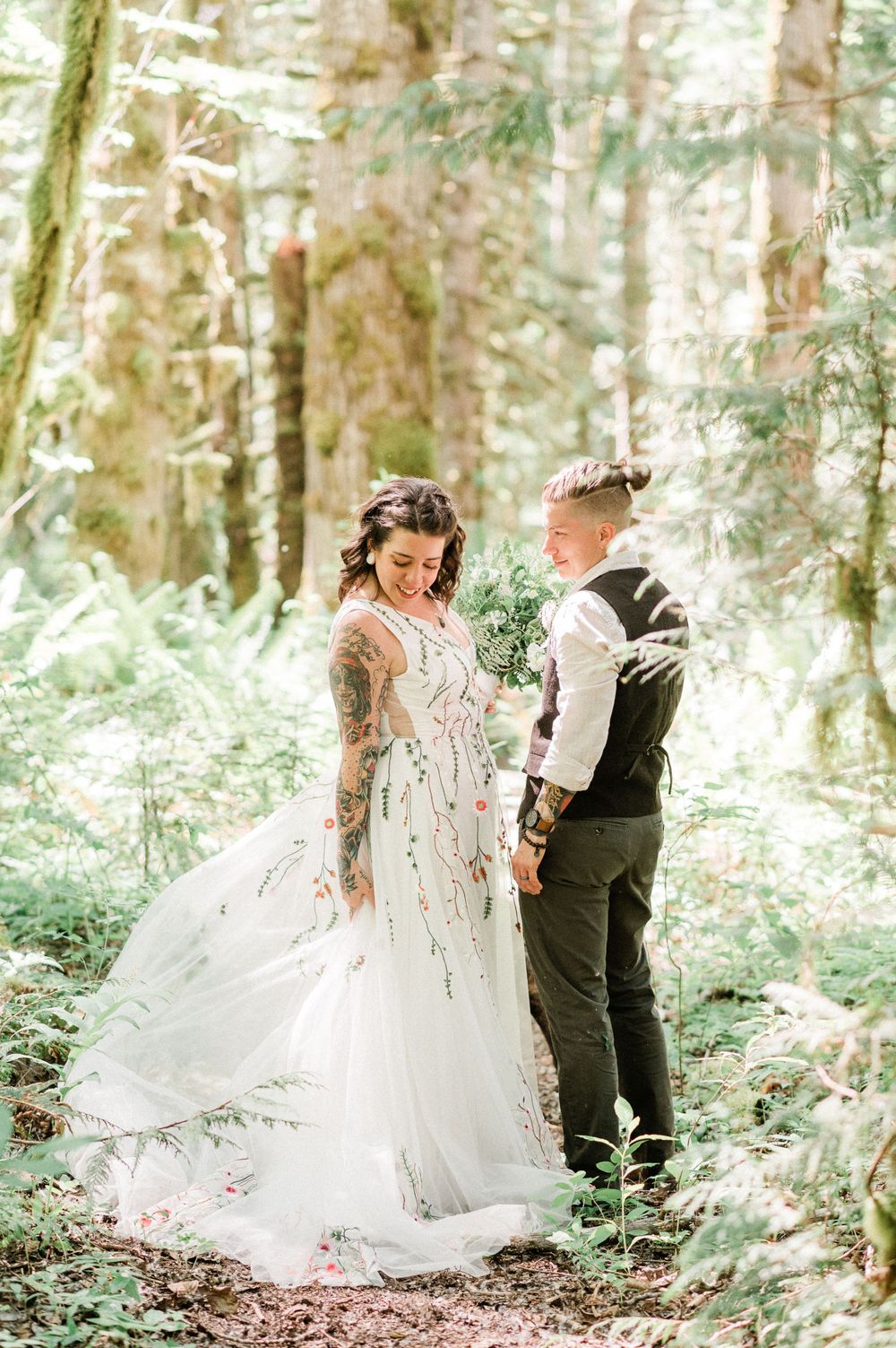 A romantic wedding couple dances and twirls through a sunlit forest in a flowing white gown and dark suit.