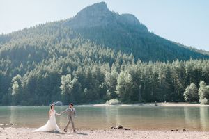 Bride and groom walk hand in hand on shoreline of Rattlensake Lake in Washington.