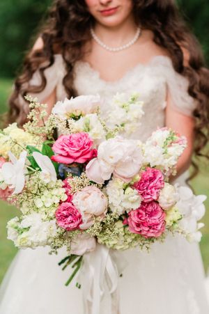 A  bride holds a romantic bridal bouquet featuring pink roses, white hydrangeas, and delicate greenery.