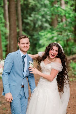 A happy couple shares joyful candid moments in a wooded outdoor setting during their wedding day