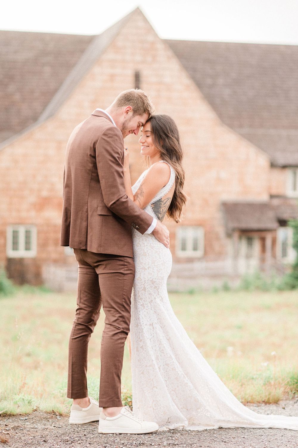 A couple in brown suit and white lace dress share romantic moments near Mt. Rainier's visitor center
