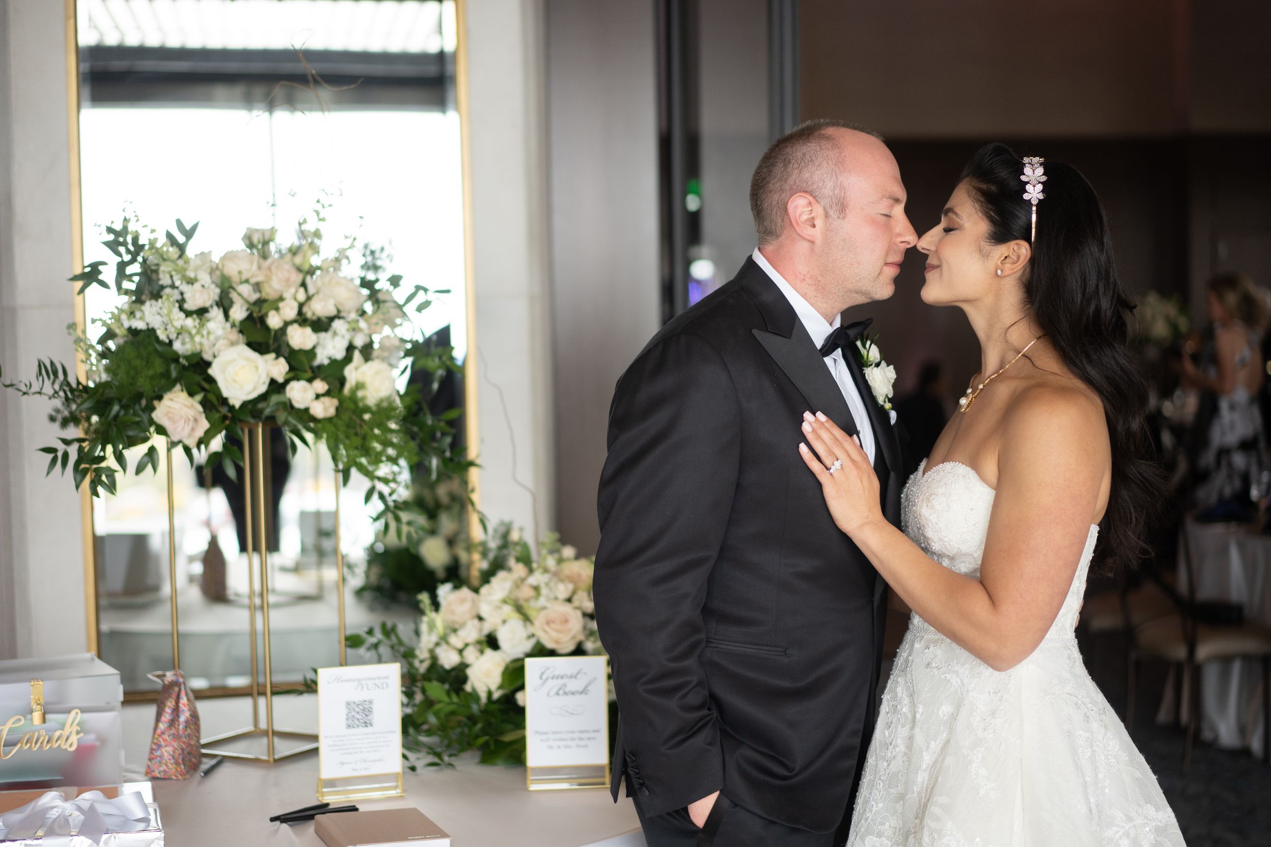 A romantic wedding moment captured at a reception with elegant white floral arrangements and decor.