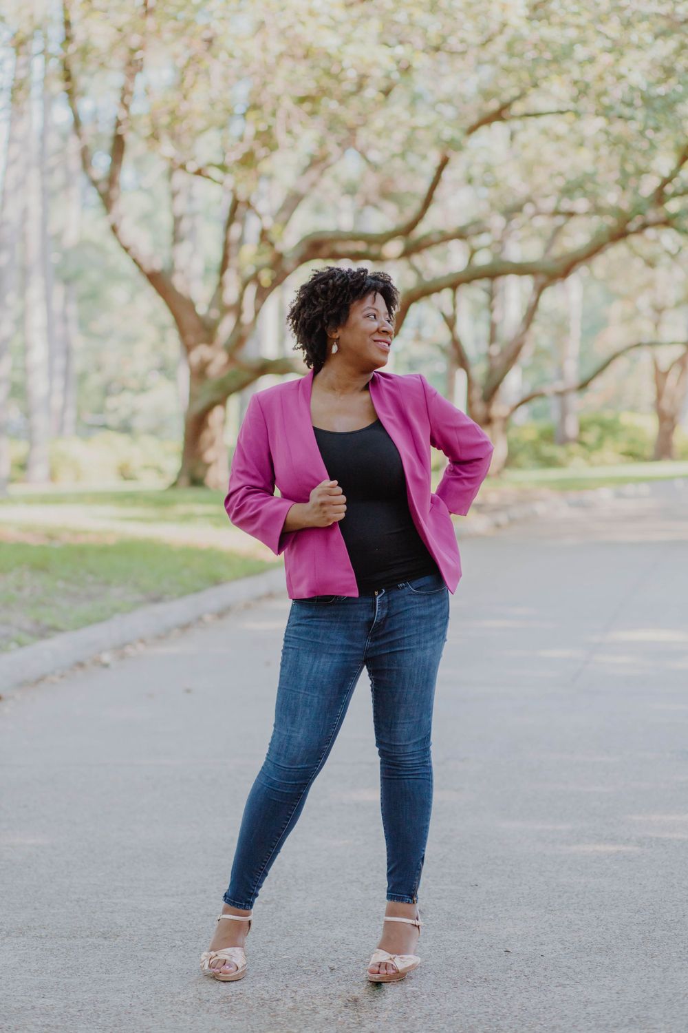 Stylish look featuring bright pink blazer and jeans on garden path.