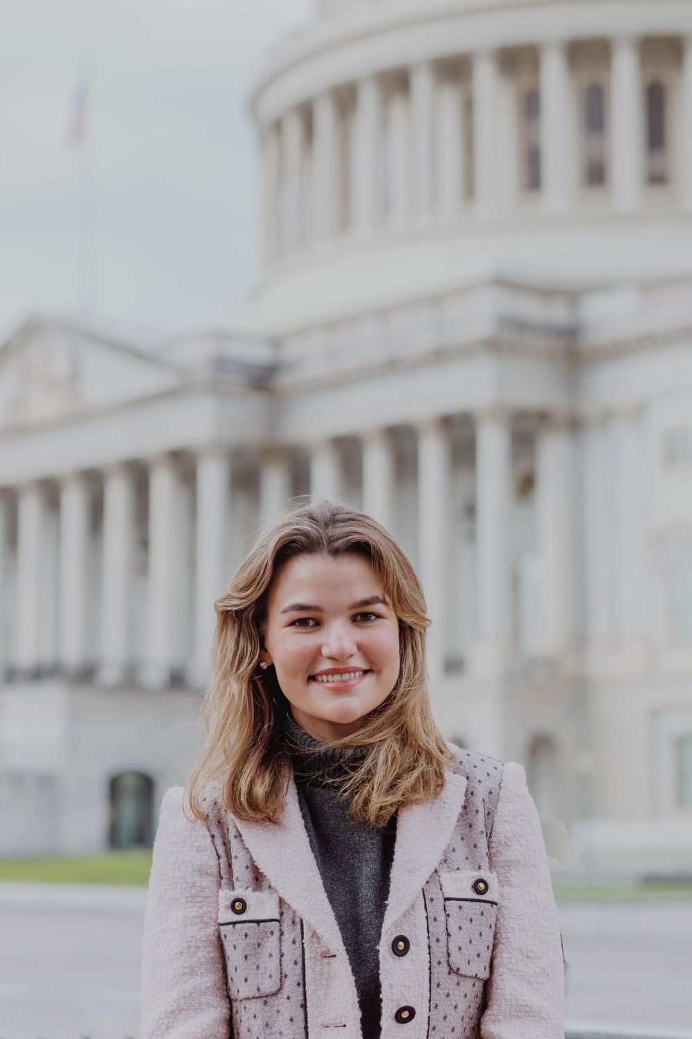 Professional portrait taken outside the U.S. Capitol building with its distinctive white dome and columns in the background.