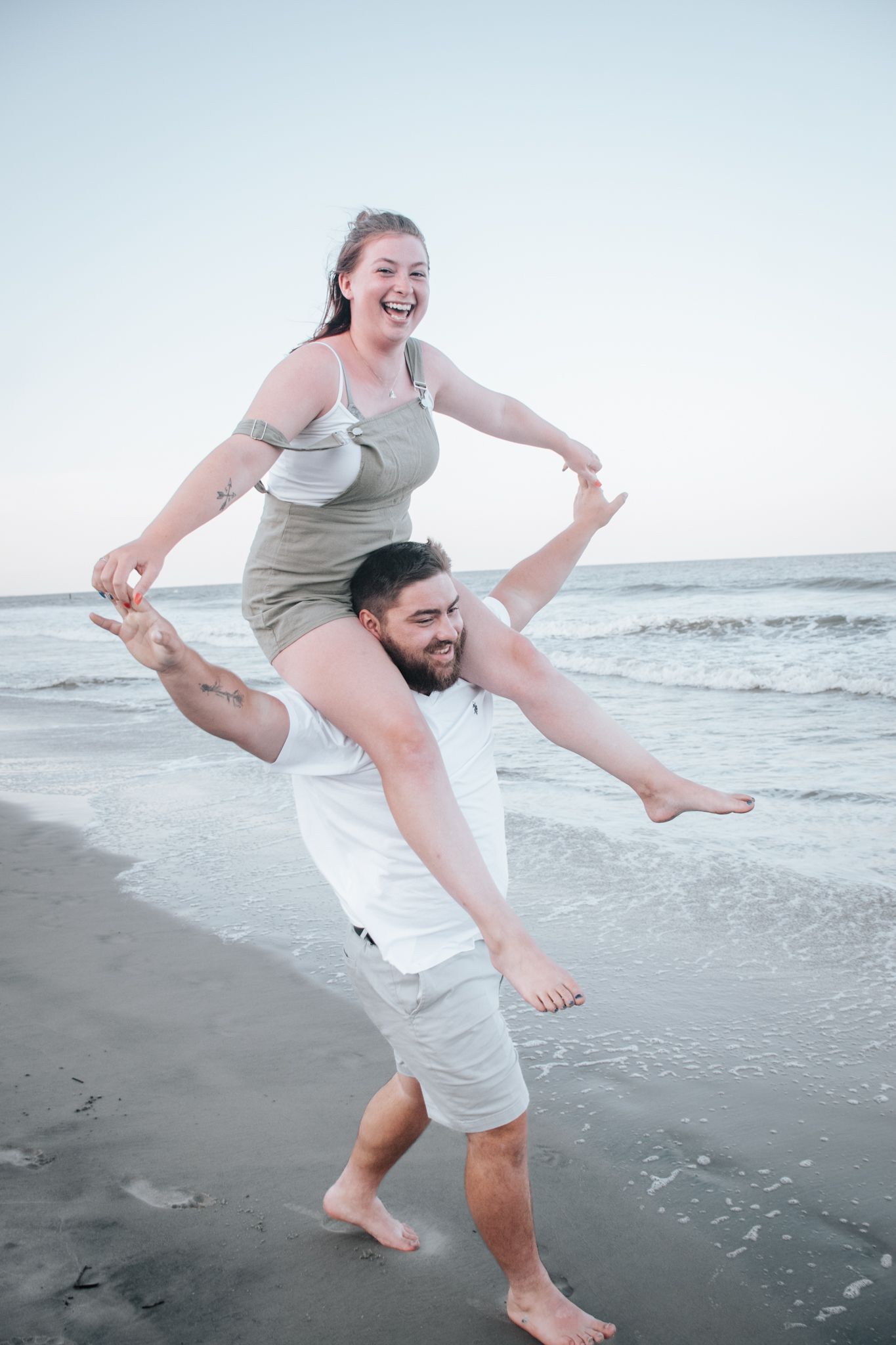 Joyful moment captured on beach as couple plays in the sand near ocean waves.