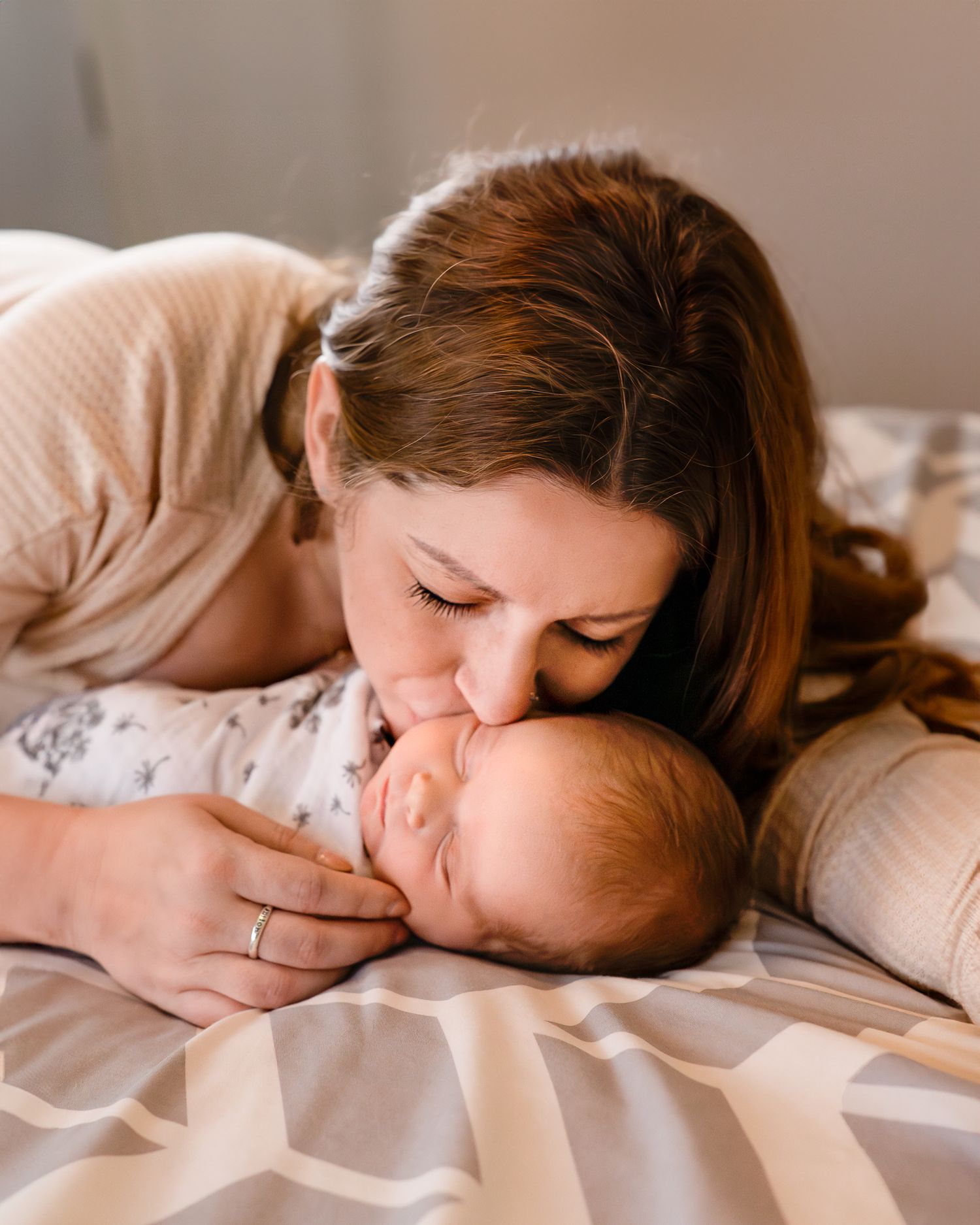 A mother kissing her newborn baby at an in-home photoshoot in Lakewood, CO.