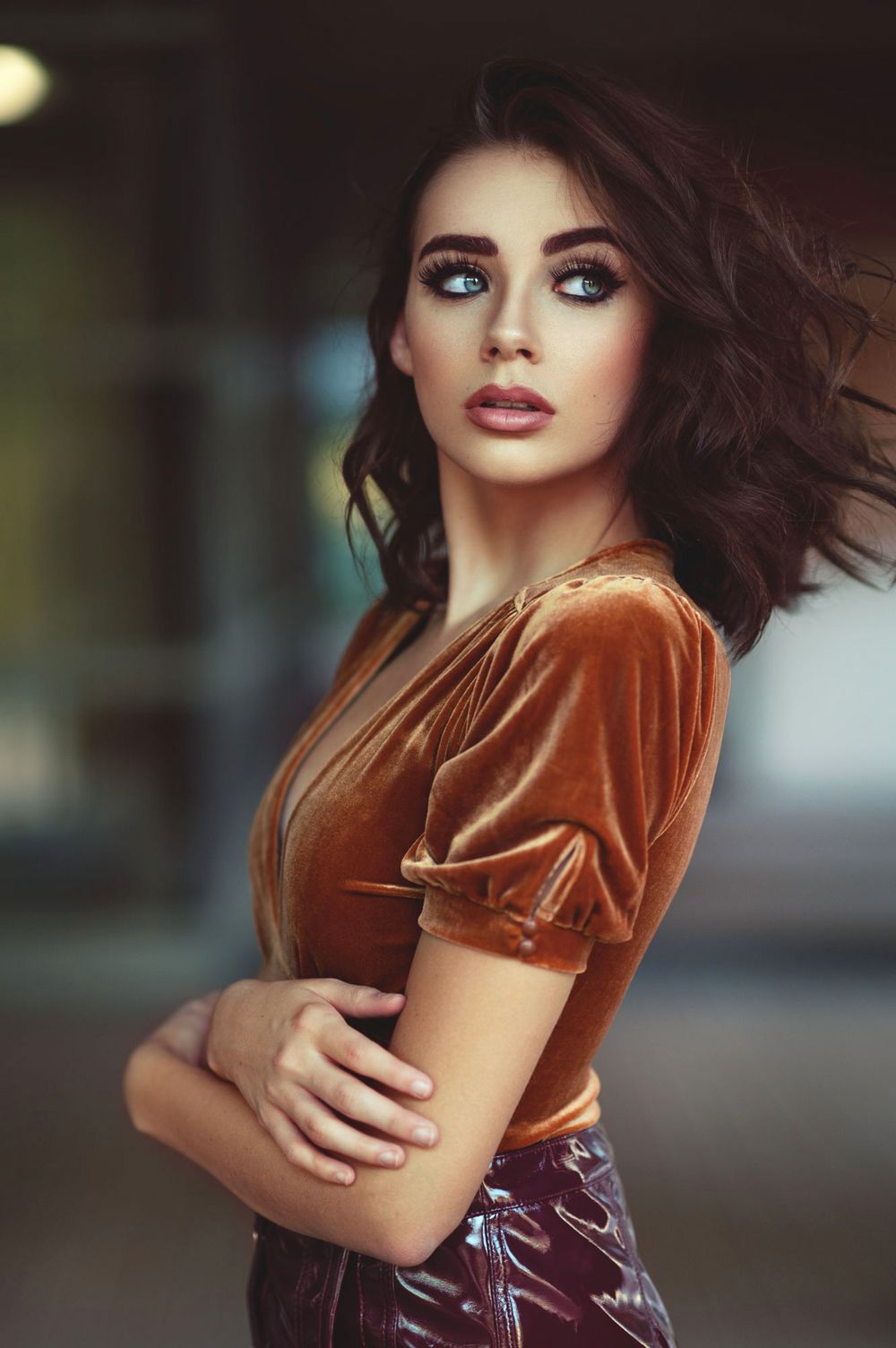 Model in velvet copper-colored dress poses against dark background.