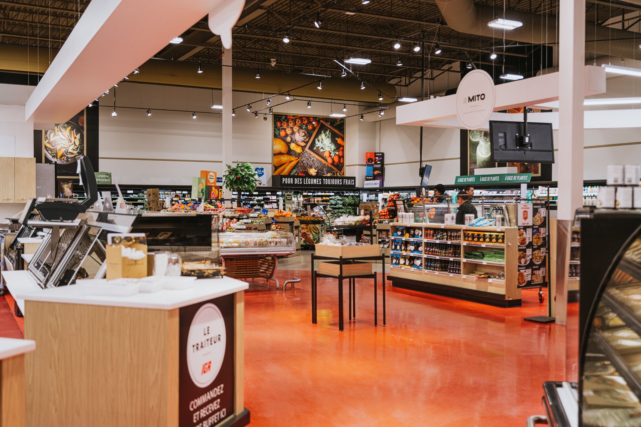 Modern supermarket interior featuring fresh food displays and shelving with bright red flooring.
