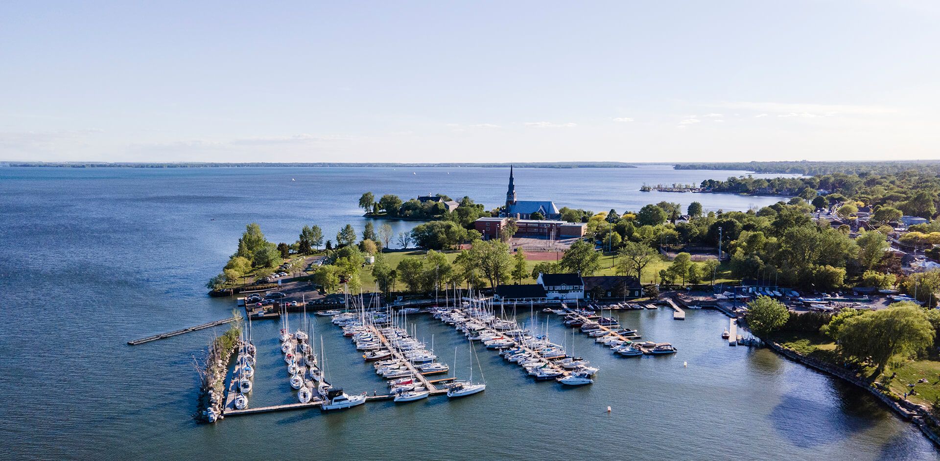 Aerial panorama of coastal marina with boats and waterfront buildings.