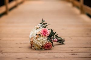 Pink and white roses arranged as wedding boutonnieres on wooden surface.