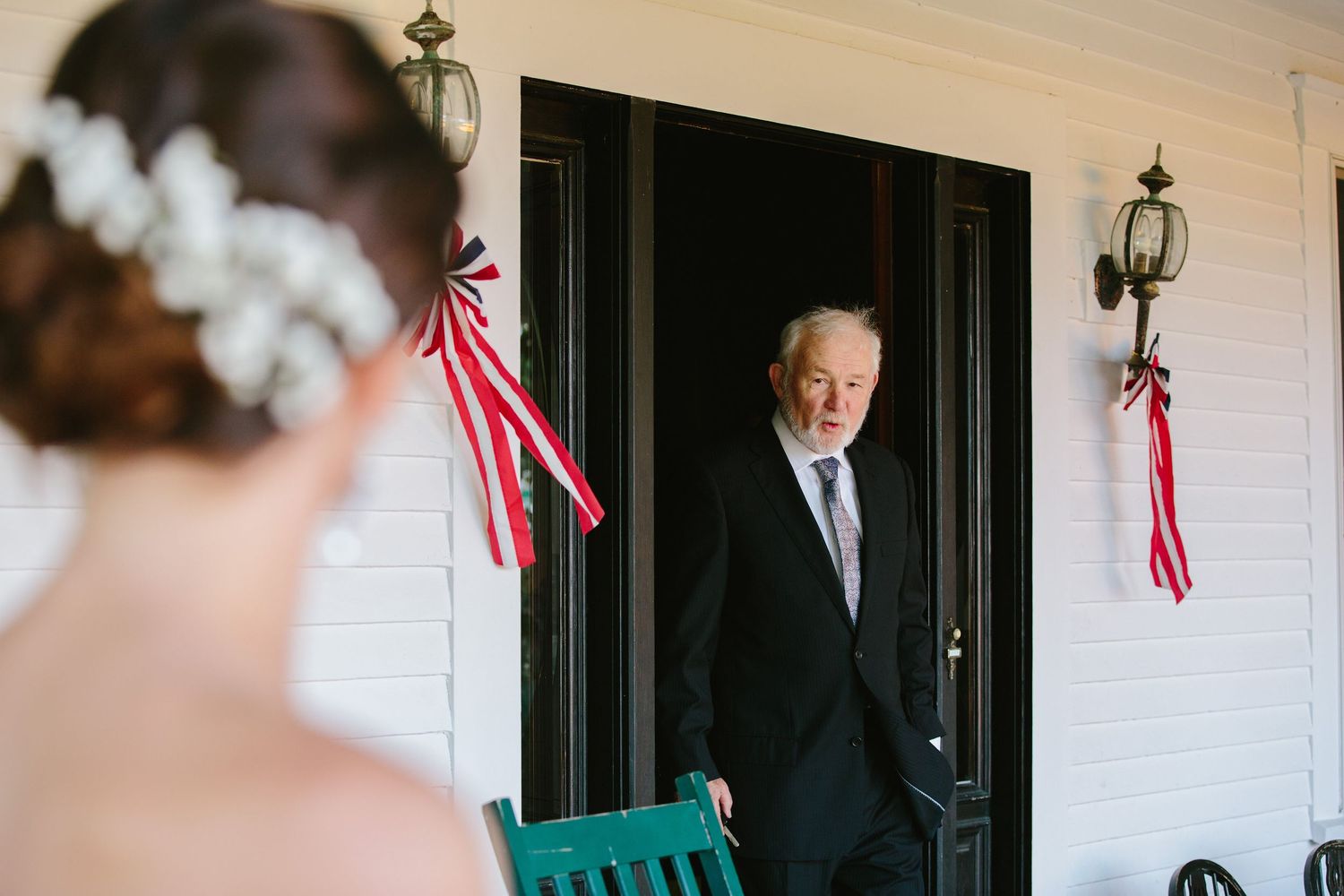 A formal gathering at a white building entrance with an American flag displayed.