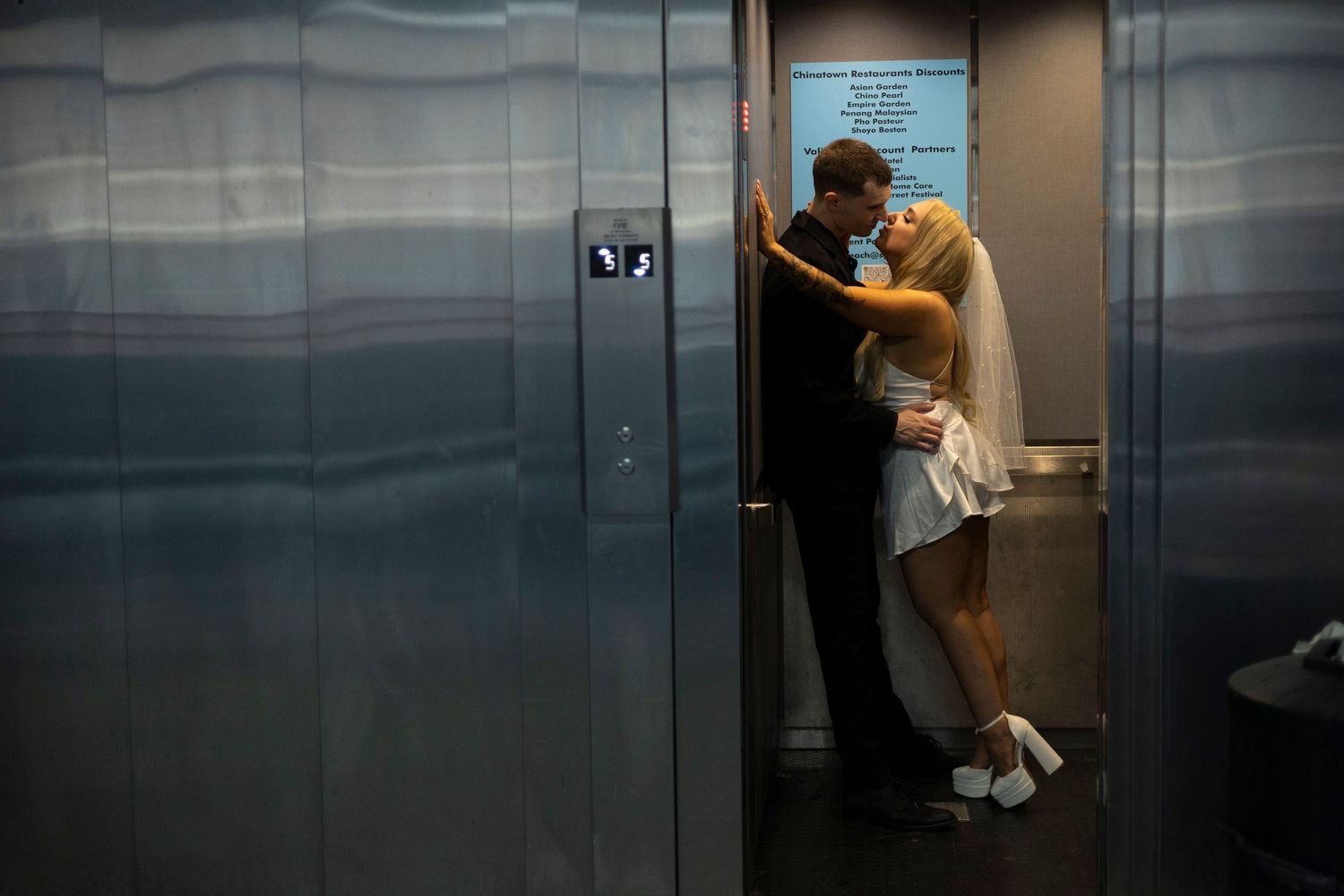 A couple shares an intimate moment while embracing in an elevator.