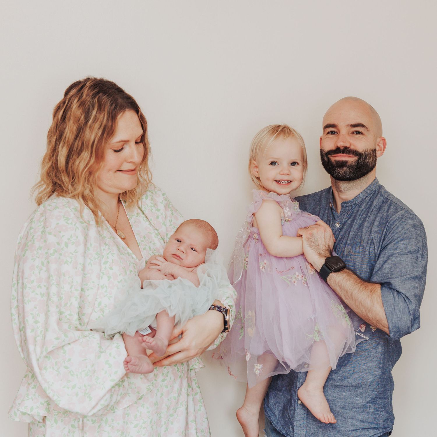 A beautiful family portrait capturing parents with their newborn baby and toddler.